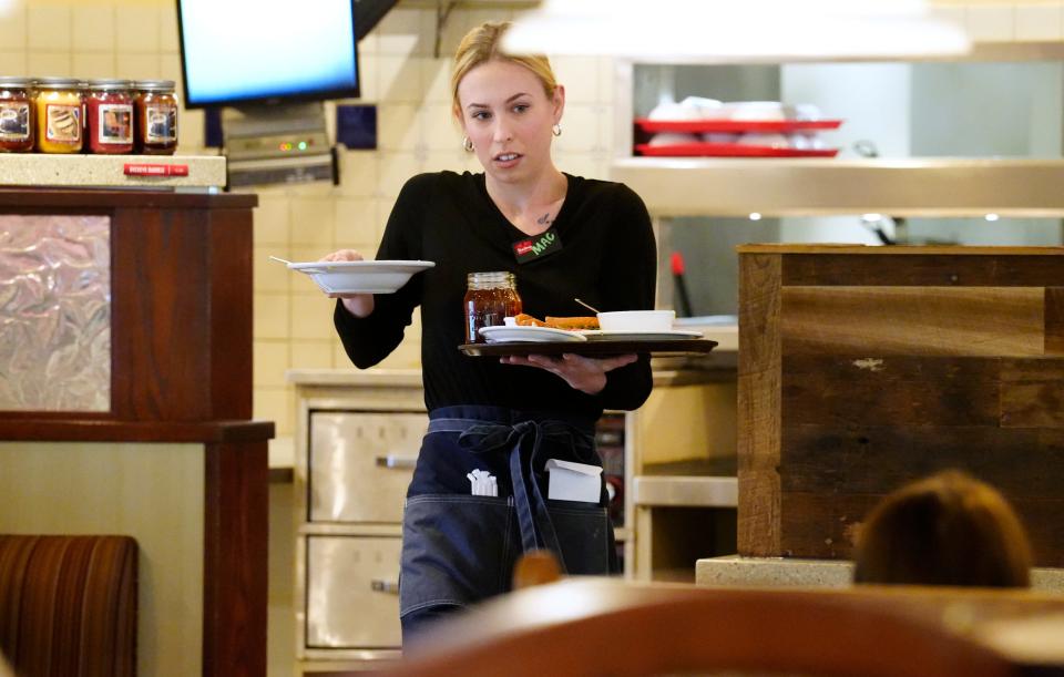 MacKenzie McCory carries food and drinks for a customers at Bob Evans restaurant in Blue Ash.