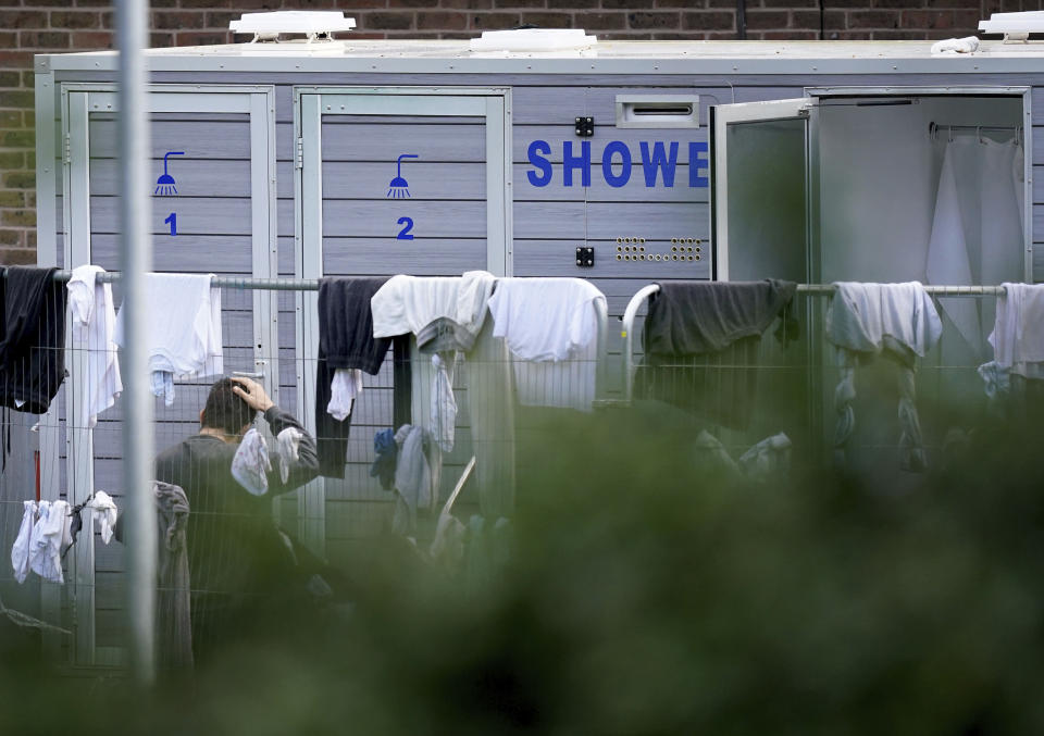 FILE - A man thought to be a migrant stands by the showers, at the Manston immigration short-term holding facility located at the former Defence Fire Training and Development Centre in Thanet, Kent, England, Tuesday, Nov. 1, 2022. Details about overcrowding and inhumane conditions at a migrant processing center in southeast England have shocked Britain and reignited a heated debate about how the Conservative government is handling a sharp increase in the number of asylum-seekers arriving on U.K. shores (Gareth Fuller/PA via AP, File)