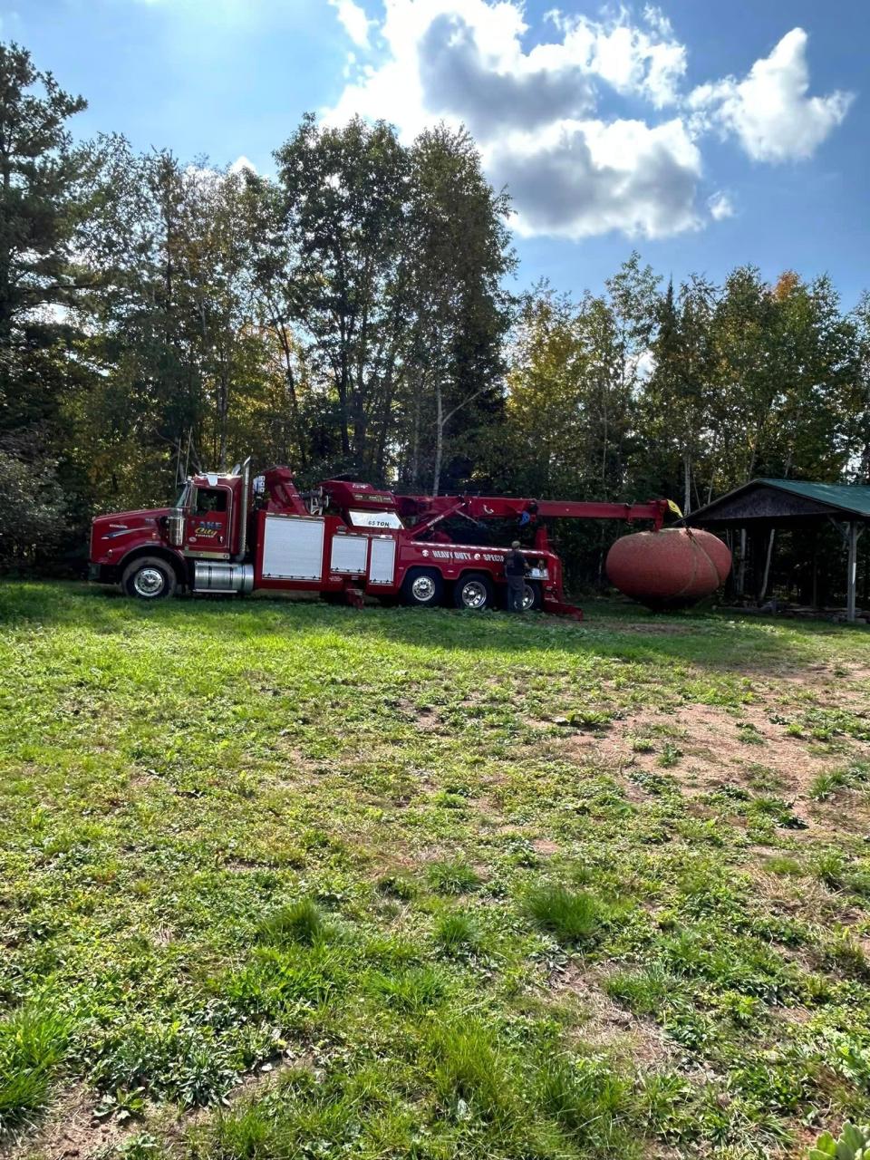 A Lake City Towing wrecker, normally used to tow heavy equipment such as semi trucks, lifts the giant ball of twine from the spot where James Frank Kotera spent 40 years making it.