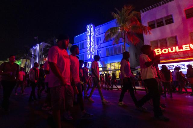 Crowds walk up and down Ocean Drive during spring break on Saturday, March 18, 2023, in Miami Beach, Fla. Miami Beach officials imposed a curfew beginning Sunday night, March 19, after two fatal shootings and rowdy, chaotic crowds that police have had difficulty controlling. (D.A. Varela/Miami Herald via AP)