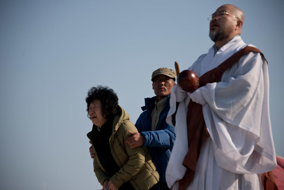 Un monje rezando junto a los familiares de pasajeros del ferry surcoreano Sewo, que se hundió hace cinco días con 476 personas a bordo, en el puerto de Jindo el 21 de abril de 2014 (AFP | Ed Jones)