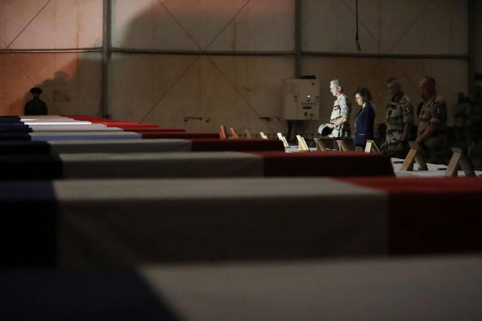 In this Wednesday, Nov. 27, 2019, photo provided by French Defense Communication and Audiovisual Department (ECPAD), French Defense Minister Florence Parly, third right, and French Army Chief of Staff Gen. Francois Lecointre pay their respects to the 13 French soldiers, in Gao, Mali. Parly arrived in northern Mali on Wednesday after a helicopter collision killed 13 French soldiers fighting Islamic State group-linked extremists, while some in the West African country debated France’s military presence. (Veronique Besnard/ECPAD via AP)