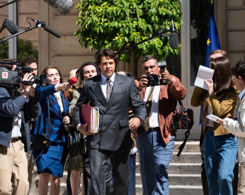 a person in a suit and tie talking to a group of people