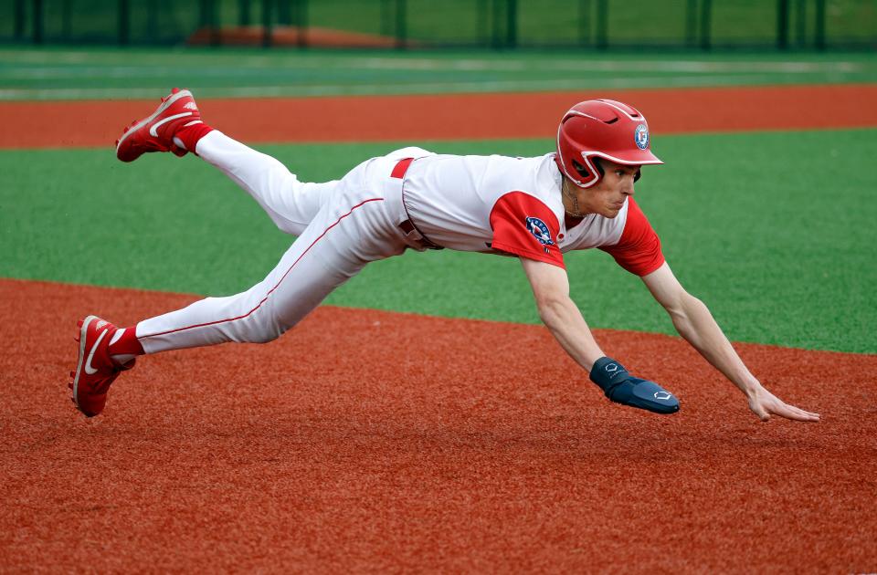 Fairport’s Sam Miller slides into third base after an errant pickoff throw at first base.