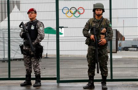 Brazilian Public-Safety National Force (L) and military police soldiers guard an entrance at the security fence outside the 2016 Rio Olympics Park in Rio de Janeiro, Brazil, July 21, 2016. REUTERS/Fabrizio Bensch