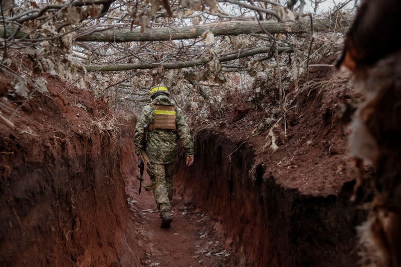 Ukrainian service member walks along a trench at a position on the front line near the city of Novoluhanske