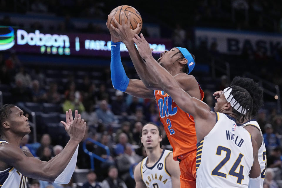 Oklahoma City Thunder guard Shai Gilgeous-Alexander (2) shoots between Indiana Pacers guard Bennedict Mathurin, left, guard Andrew Nembhard, center, and guard Buddy Hield (24) in the first half of an NBA basketball game Wednesday, Jan. 18, 2023, in Oklahoma City. (AP Photo/Sue Ogrocki)