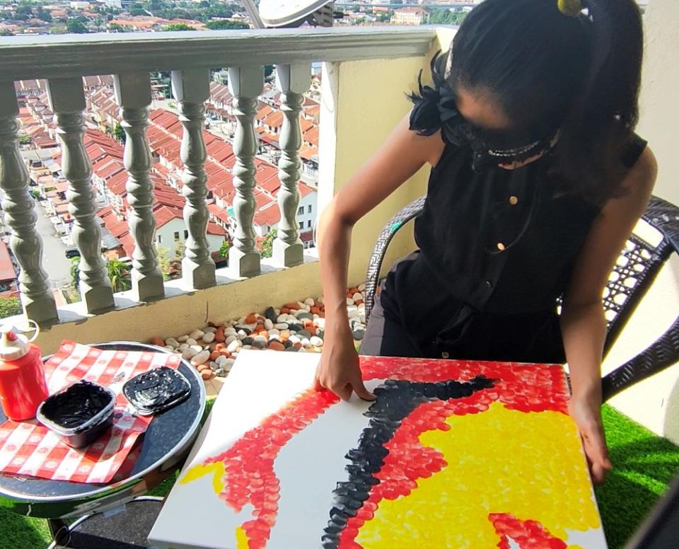 Vivian Ng using her thumbprint to create the portrait of Tunku Abdul Rahman. — Picture courtesy of Vivian Ng