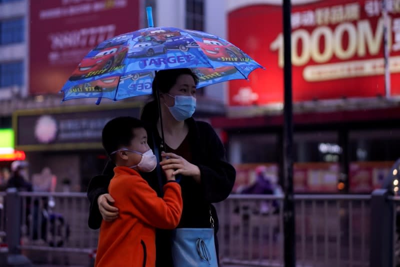 People wearing face masks walk in Jingzhou