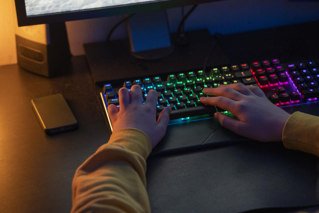  Hands on a multi colored gaming keyboard. 