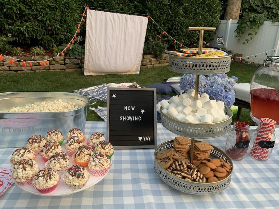 diy backyard movie night ideas picnic table with popcorn cupcakes smores station and now showing sign