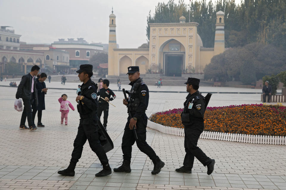 FILE - In this Nov. 4, 2017, file photo, Uighur security personnel patrol near the Id Kah Mosque in Kashgar in western China's Xinjiang region. China says on Monday, March 18, 2019 it has arrested nearly 13,000 people it describes as terrorists in the traditionally Islamic region of Xinjiang since 2014 and broken up hundreds of "terrorist gangs." The figures were included in a government report on the situation in the restive northwestern territory that seeks to respond to growing criticism over the internment of an estimated 1 million members of the Uighur and other predominantly Muslim ethnic groups. (AP Photo/Ng Han Guan, File)