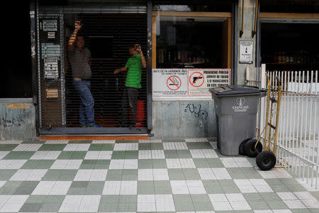 Men stand inside a closed liquor store during a blackout in Caracas, Venezuela March 7, 2019. REUTERS/Manaure Quintero NO RESALES. NO ARCHIVES.