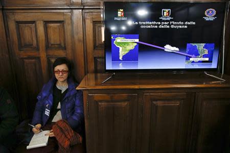 A reporter sits next to a screen showing a police operation during a news conference with Italian and U.S. investigators in Rome February 11, 2014. REUTERS/Tony Gentile