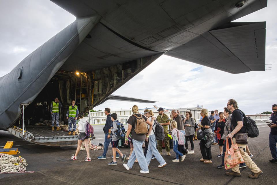 In this photo provided by the Australian Department of Defence, Australian and other tourists board an Australian Airforce Hercules as they prepare to depart from Magenta Airport in Noumea, New Caledonia, Tuesday, May 21, 2024. Australia and New Zealand have sent airplanes to New Caledonia to begin bringing home stranded citizens from the violence-wracked French South Pacific territory. (LAC Adam Abela/Royal Australian Airfare via AP)