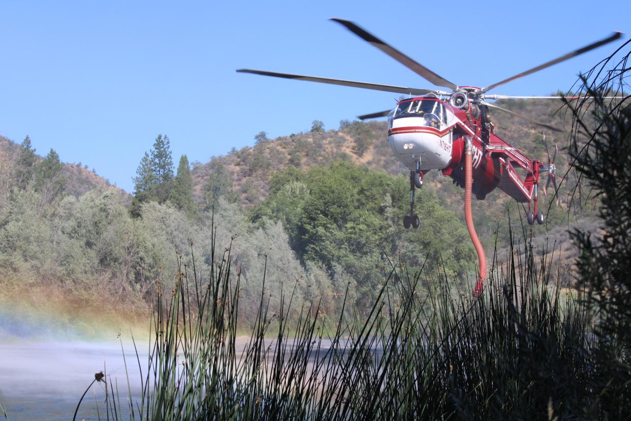 A Helicopter Transport Service helicopter fills with water by dipping its snorkel in the Klamath River as part of firefighting efforts on the McKinney Fire in western Siskiyou County.