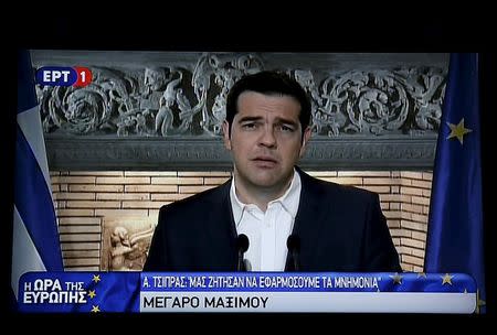 Greek Prime Minister Alexis Tsipras is seen on a television monitor whille addressing the nation early June 27, 2015. REUTERS/Pool