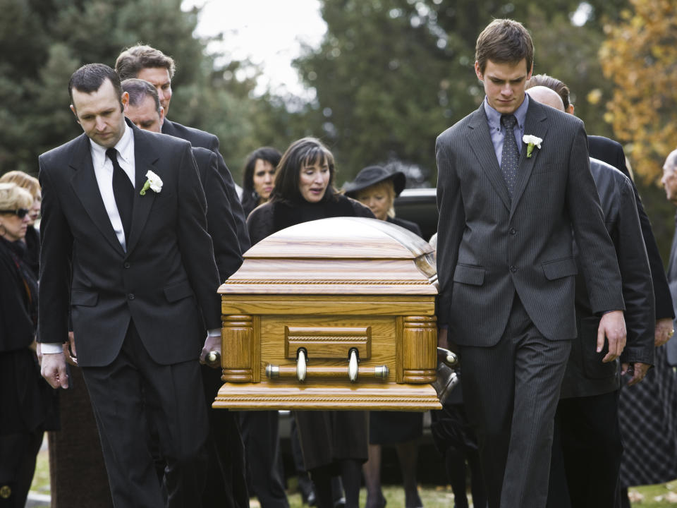 Mourners carrying a coffin at a funeral.