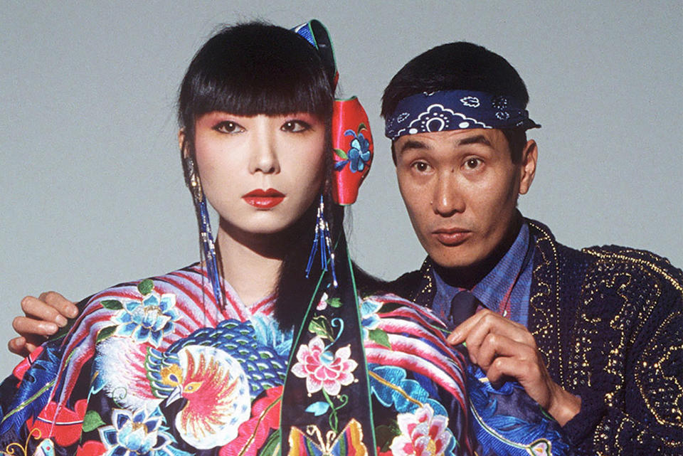 Japanese fashion designer Kansai Yamamoto, right, checks the dress of model Sayoko Yamaguchi at a studio in Tokyo, in Nov. 1982. Yamamoto, known for his avant-garde and colorful work that included flamboyant costumes of the late rock icon David Bowie has died of leukemia, his company said on Monday, July 27, 2020. He was 76. (Kyodo News via AP)