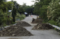 This Oct. 3, 2019 photo shows mounds of dirt and rock placed their by vigilantes in a zig-zag pattern on the highway leading in from Jalisco, on the outskirts of Tepalcatepec, Michoacan state, Mexico. Some small-scale avocado growers are taking up arms to guard against thieves and drug cartel extortionists, while others have piled mounds of dirt and rock on highways leading into their communities to slow down incoming vehicles and make them vulnerable to gunfire. (AP Photo/Marco Ugarte)