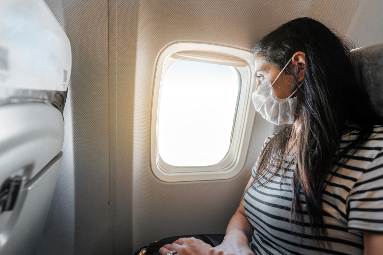 woman sitting on airplane with a mask