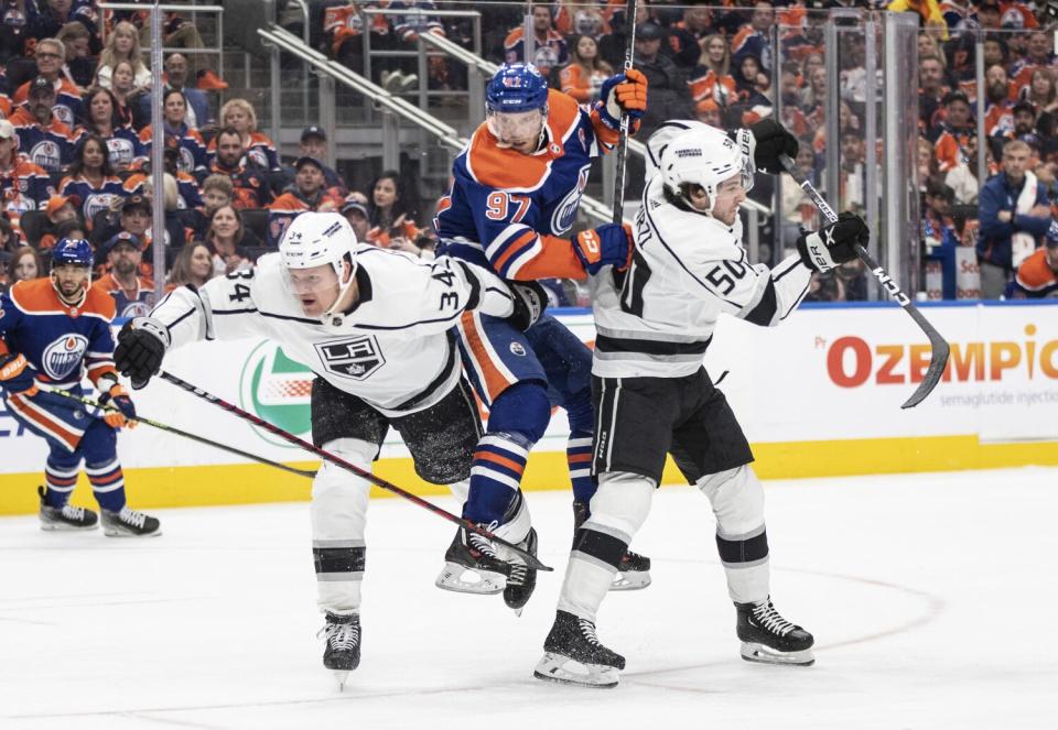 Kings' Arthur Kaliyev and Sean Durzi check Edmonton Oilers' Connor McDavid during the second period.