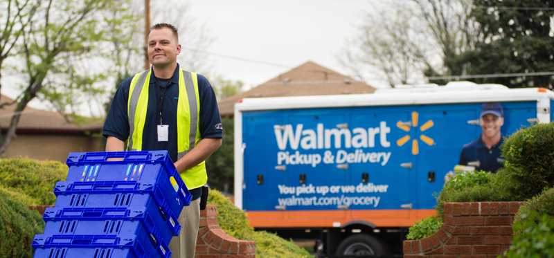 Walmart employee unloading blue totes from truck.