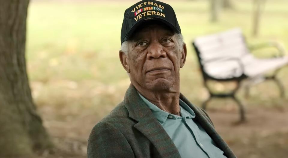 Elderly man wearing a 'Vietnam Veteran' cap sitting in a park, looking thoughtful