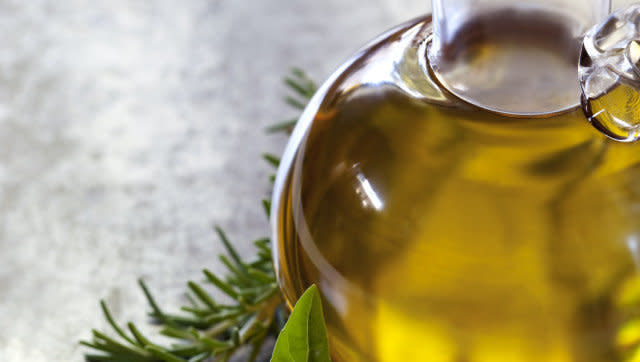 Bottle of olive oil, with fresh basil and rosemary.