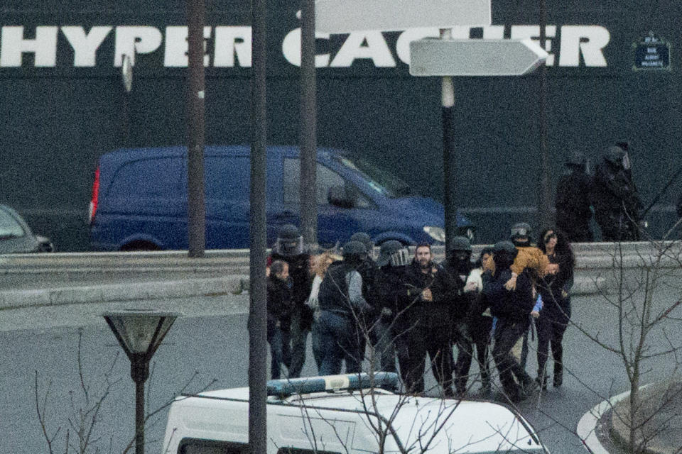 FILE - In this Jan. 9, 2015 file photo, security officers escort released hostages after they stormed a kosher market to end a hostage situation, Paris. The January 2015 attacks against Charlie Hebdo and, two days later, a kosher supermarket, touched off a wave of killings claimed by the Islamic State group across Europe. Seventeen people died along with the three attackers. Thirteen men and a woman accused of providing the attackers with weapons and logistics go on trial on terrorism charges Wednesday Sept. 2, 2020. (AP Photo/Michel Euler, File)