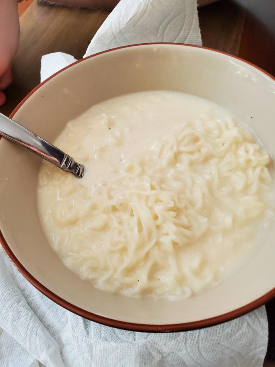 A bowl of ramen in watery alfredo sauce