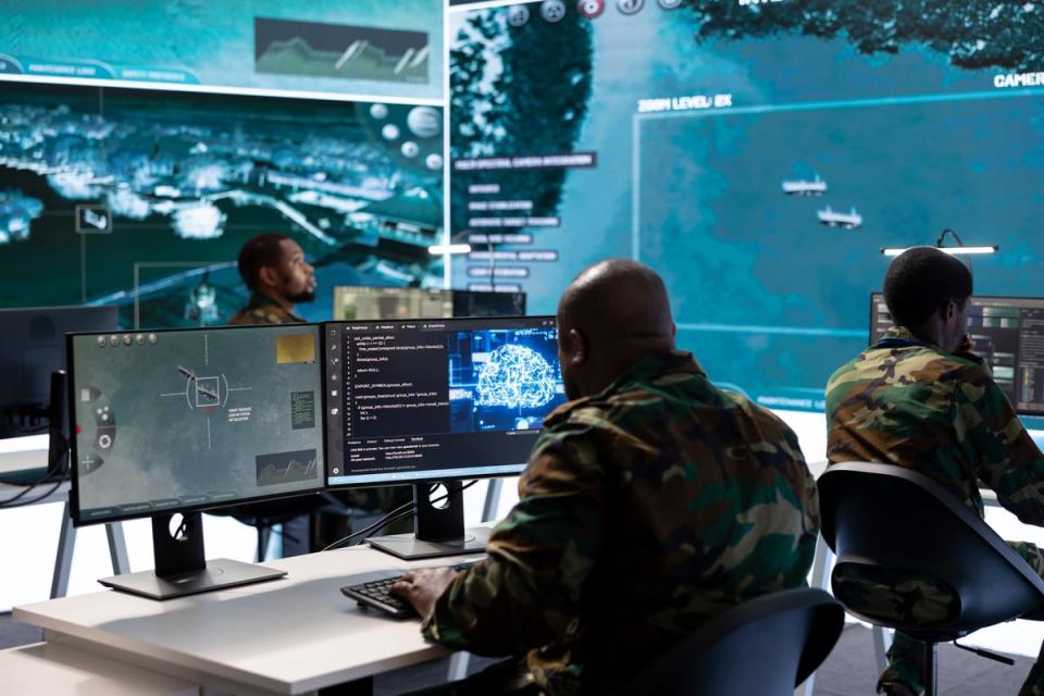 Three members of the military in a high-tech control room.