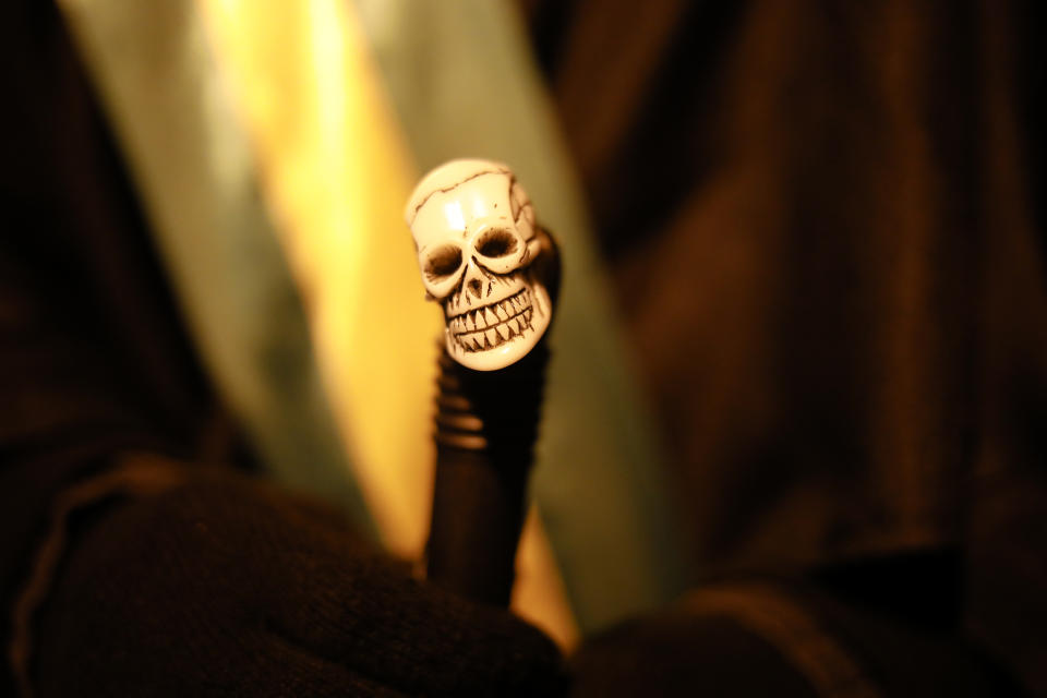 Brazilian activist and artist Rafael Puetter, holds his walking stick, decorated with a small skull, prior to his one-man protest through Berlin, Germany, late Tuesday, April 6, 2021. The multimedia artist starts his performance, dressed as the grim reaper,,at the Brazilian embassy in Berlin at midnight every night to protest against Brazil's COVID-19 policies. Rafael Puetter walks to the Brandenburg Gate and then to the nearby German parliament building, in front of which he counts out a sunflower seed to represent each of the lives that were lost over the past 24 hours in Brazil because of the coronavirus pandemic. (AP Photo/Markus Schreiber)