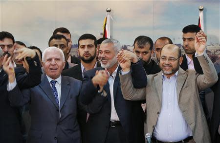 Senior Fatah official Azzam Al-Ahmed (L), head of the Hamas government Ismail Haniyeh (C) and senior Hamas leader Moussa Abu Marzouq hold their hands after announcing a reconciliation agreement in Gaza City, in this April 23, 2014 file picture. REUTERS/Suhaib Salem/Files