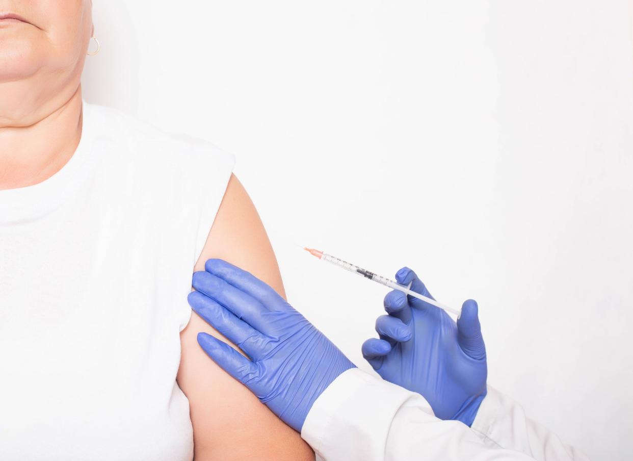 A doctor vaccinates an adult elderly woman in the shoulder