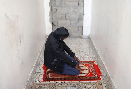 An African migrant prays at a detention centre in Zawiya, northern Libya May 27, 2014. REUTERS/Ahmed Jadallah