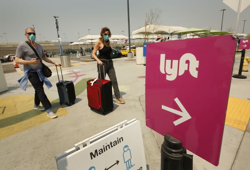 LAX AIRPORT, CA - AUGUST 20: Passengers make their way to the rideshare location at LAX as Uber and Lyft drivers held a moving rally as part of a statewide day of action to demand that both ride-hailing companies follow California law and grant drivers "basic employee rights" and to "denounce the corporations' efforts to avoid their responsibilities to workers." Uber and Lyft threatened to suspend services in California Thursday night but a court granted Uber and Left a stay to a preliminary injunction requiring both rideshare companies to reclassify their drivers as employees, meaning the rideshare companies will not suspend service in California tonight as they threatened. Los Angeles on Thursday, Aug. 20, 2020 in LAX Airport, CA. (Al Seib / Los Angeles Times