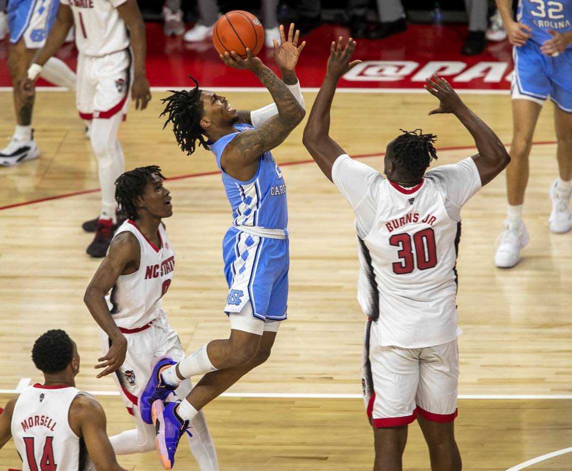 North Carolina’s Caleb Love (2) drives to the basket against N.C. State’s D.J. Burns (30) during the first half on Sunday, February 19, 2023 at PNC Arena in Raleigh, N.C.
