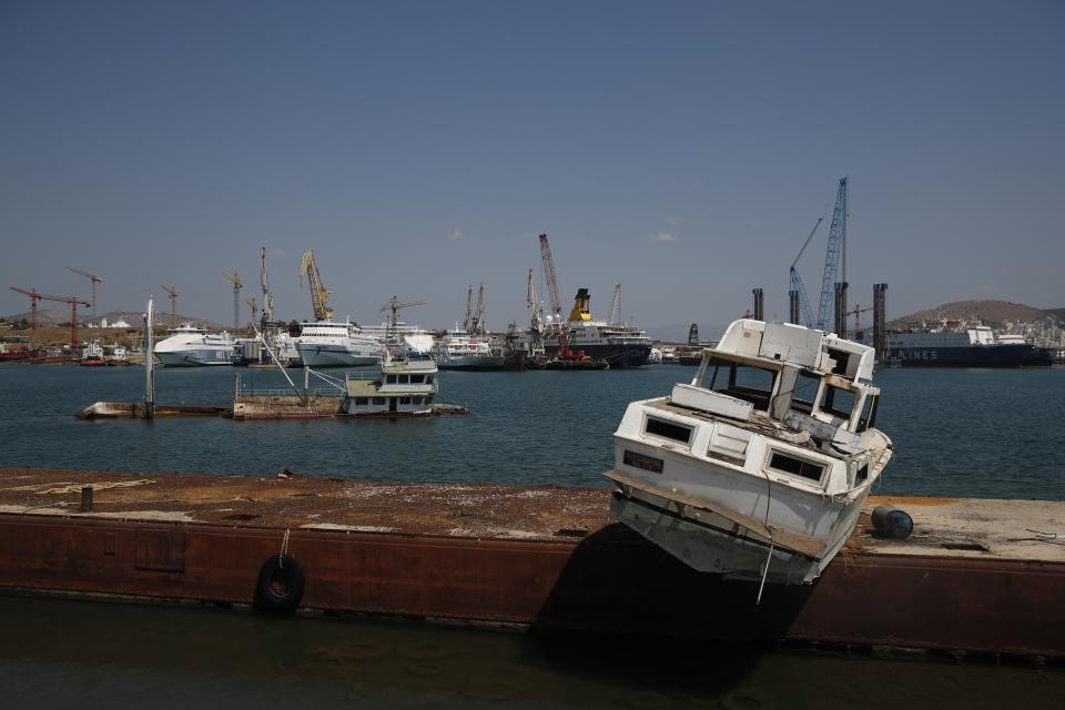 A half sunken boat and an abandoned vessel on a platform are seen on Salamina island, west of Athens, on Thursday, Aug. 22, 2019. Greece this year is commemorating one of the greatest naval battles in ancient history at Salamis, where the invading Persian navy suffered a heavy defeat 2,500 years ago. But before the celebrations can start in earnest, authorities and private donors are leaning into a massive decluttering operation. They are clearing the coastline of dozens of sunken and partially sunken cargo ships, sailboats and other abandoned vessels. (AP Photo/Thanassis Stavrakis)