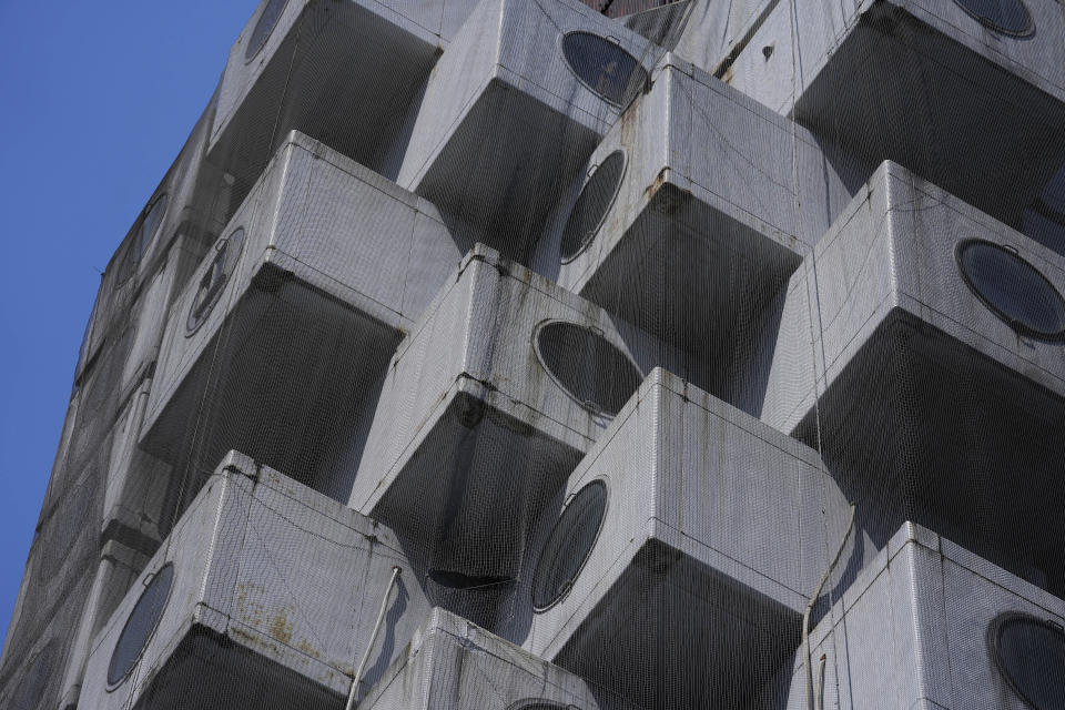 The Nakagin Capsule Tower, a famed capsule hotel in the Ginza district, shows its unique architecture of small cubic rooms, as parts of the capsule hotel was being demolished, in Tokyo on April 8, 2022. It’s now being demolished in a careful process that includes preserving some of its 140 capsules, to be shipped to museums around the world. (AP Photo/Hiro Komae)