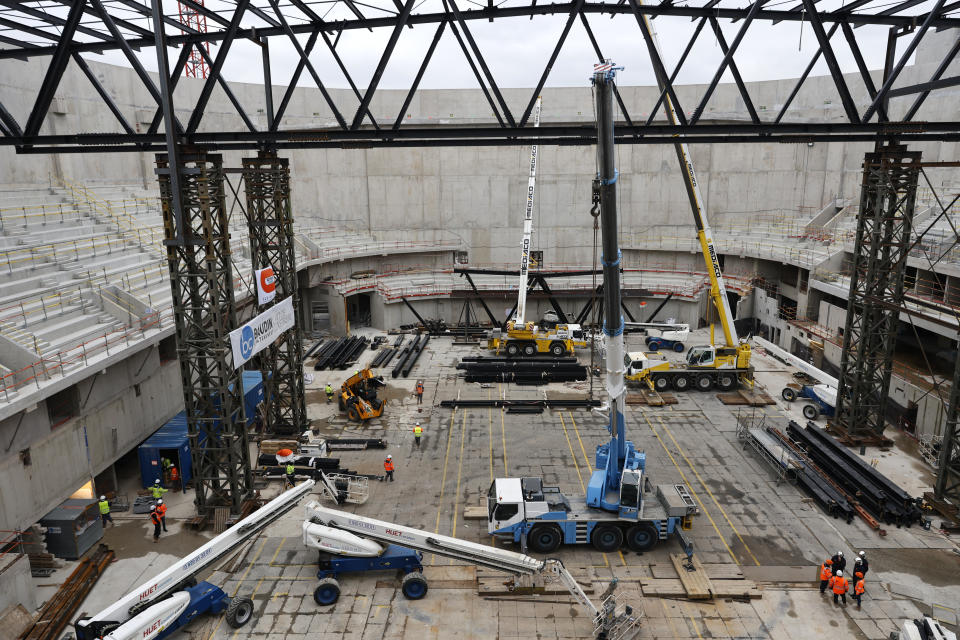 Workers stand at the Paris2024 Olympics Porte de la Chapelle Arena building site, Monday, Jan. 23, 2023 in Paris. The olympic venue will host the badminton and rhythmic gymnastics event and para badminton and para powerlifting with a capacity of 6,700 to 7,000 spectators. (AP Photo/Lewis Joly)