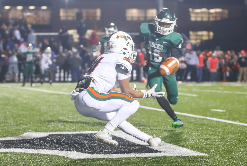 Frederick Douglass' Derion Talbert makes a late fourth-quarter catch to help the Broncos tie the game against Trinity as Trinity's Sekou Kamara looks on. The Shamrocks defeated the Broncos, 14-7, in overtime Friday night.