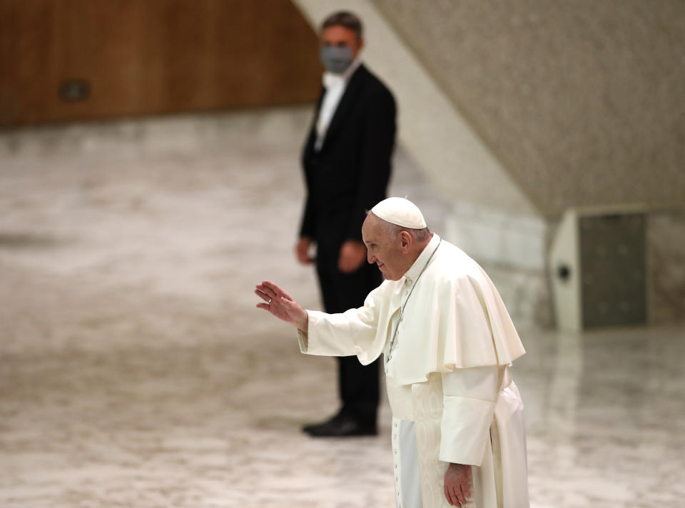 Pope Francis salutes faithful at the end of his weekly general audience in the Paul VI Hall at the Vatican, Wednesday, Oct. 28, 2020. Pope Francis has blamed “this lady COVID” for forcing him to keep his distance from the faithful during his general audience, which was far smaller than usual amid soaring coronavirus infections in Italy. (AP Photo/Alessandra Tarantino)