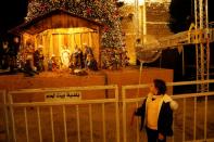 Girl looks at an artwork showing a nativity scene made of olive wood at Manger Square in Bethlehem in the Israeli-occupied West Bank
