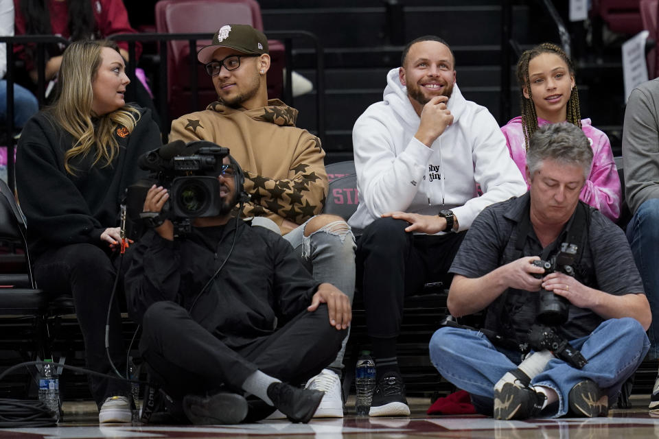 Golden State Warriors' Stephen Curry, second from right, and his daughter Riley, right, sit courtside during the first half of an NCAA college basketball game between Stanford and Southern California in Stanford, Calif., Friday, Feb. 17, 2023. (AP Photo/Godofredo A. Vásquez)