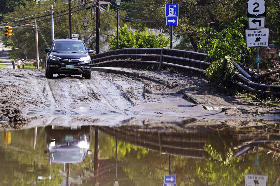 A driver stops on a mud-covered bridge while deciding whether to drive through flood waters of the Winooski River, Wednesday, July 12, 2023, in Montpelier, Vt. The driver decided to back up, following a storm that dumped nearly two months of rain in two days. Vermonters are cleaning up from the deluge of water. (AP Photo/Charles Krupa)