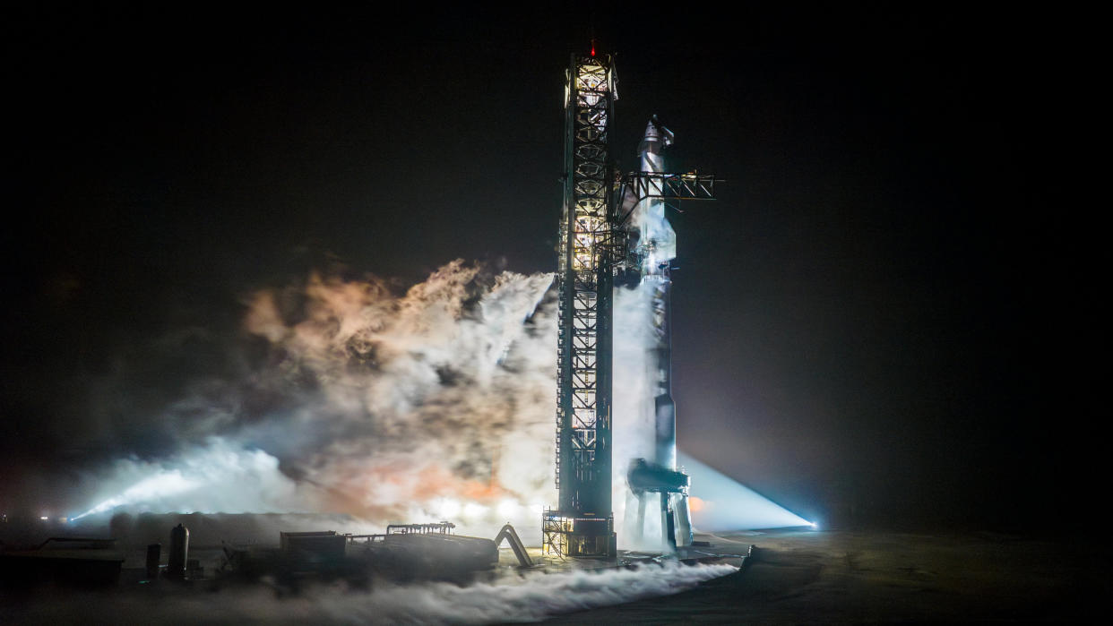  A towering Starship Flight 3 rocket and Super Heavy booster atop the launch pad at night in a fueling test. 