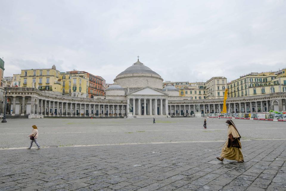 A nun walks in an empty Piazza del Plebiscito in Naples, southern Italy, on the first day after being declared a red zone, Sunday, Nov. 15, 2020. The regions of Italy that include the cities of Naples and Florence were declared coronavirus red zones, the latest signals of the dire condition of Italian hospitals struggling with a surge of new admissions. (Alessandro Pone/LaPresse via AP)