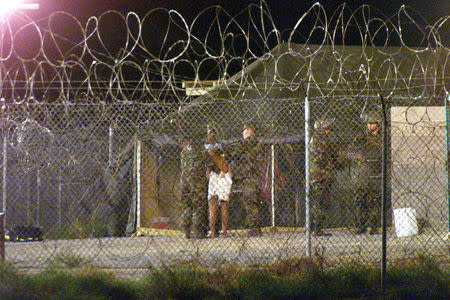 FILE PHOTO: Marines at Camp X-Ray at the Naval Base at Guantanamo Bay, Cuba escort a newly arriving detainee into a processing tent after being showered in this February 7, 2002 file photo. REUTERS/Marc Serota/File Photo