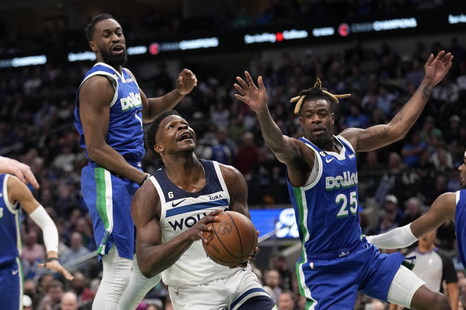 Minnesota Timberwolves guard Anthony Edwards, center, drives to the basket as Dallas Mavericks' Theo Pinson, left, and Reggie Bullock (25) defend in the first half of an NBA basketball game, Monday, Feb. 13, 2023, in Dallas. (AP Photo/Tony Gutierrez)